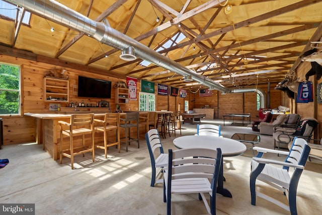 dining area featuring wood walls and lofted ceiling