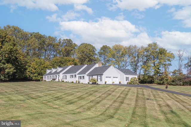 ranch-style home featuring a front yard, a chimney, a garage, and aphalt driveway