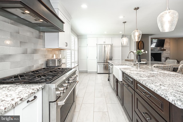 kitchen with white cabinets, appliances with stainless steel finishes, dark brown cabinetry, and premium range hood