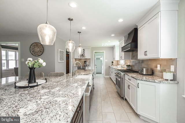 kitchen with custom exhaust hood, white cabinetry, high end stainless steel range oven, and hanging light fixtures