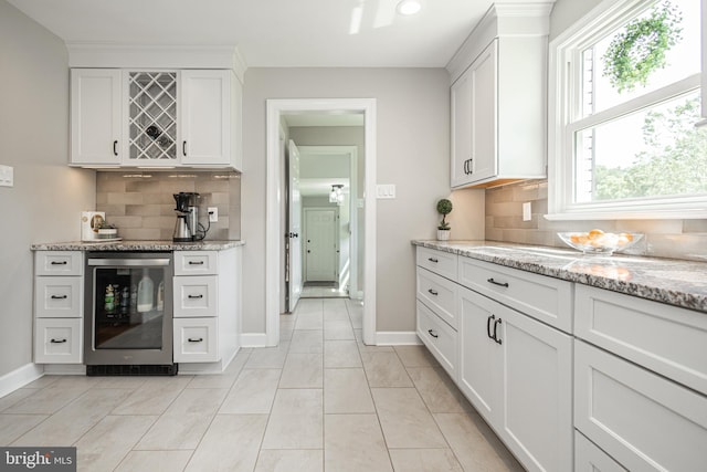 kitchen featuring light stone counters, white cabinetry, backsplash, and beverage cooler