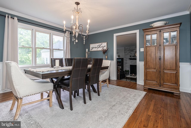 dining room featuring a fireplace, crown molding, dark hardwood / wood-style flooring, and an inviting chandelier