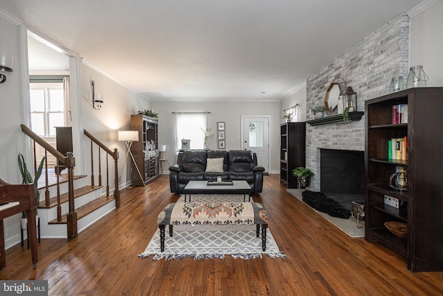 living room with dark hardwood / wood-style flooring, a brick fireplace, and crown molding