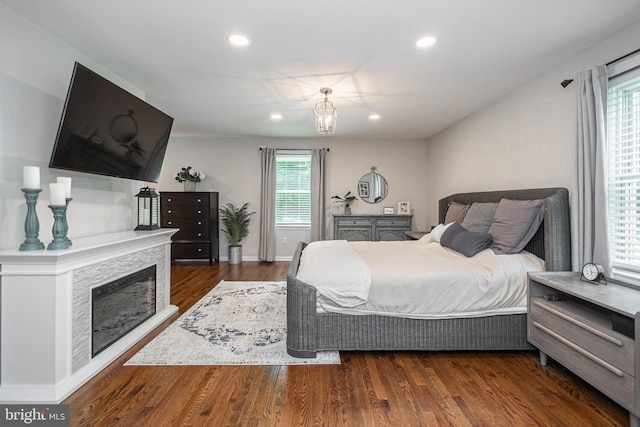 bedroom with dark hardwood / wood-style flooring and a fireplace