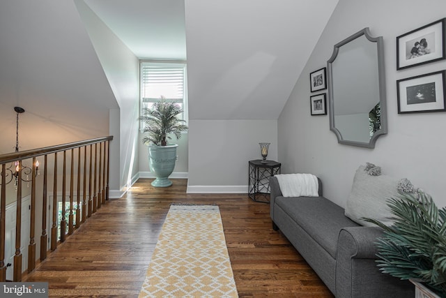 living area with dark hardwood / wood-style floors, vaulted ceiling, and a notable chandelier