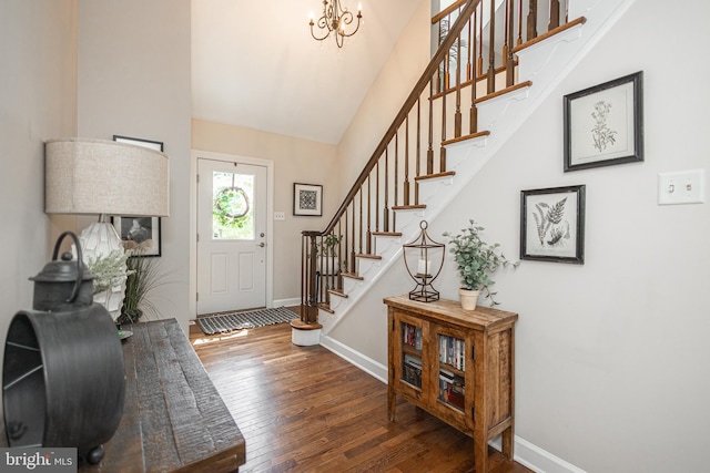 entrance foyer featuring lofted ceiling, dark wood-type flooring, and a notable chandelier