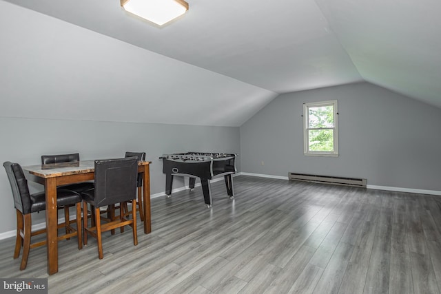 dining space featuring hardwood / wood-style flooring, vaulted ceiling, and a baseboard radiator