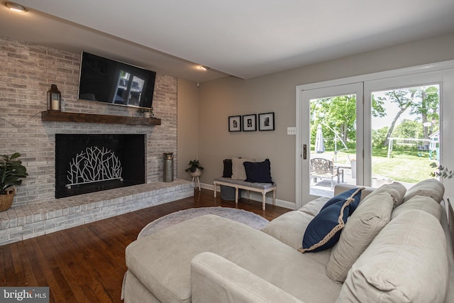 living room featuring dark hardwood / wood-style flooring and a brick fireplace