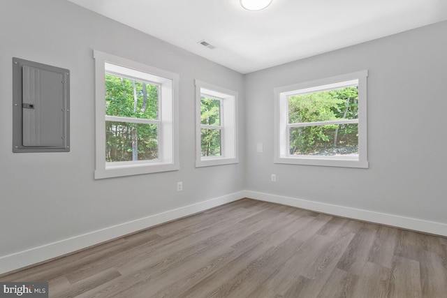 spare room featuring electric panel and light hardwood / wood-style flooring