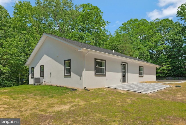 rear view of property with central AC unit, a patio, and a lawn