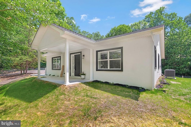 rear view of house featuring a lawn and central AC