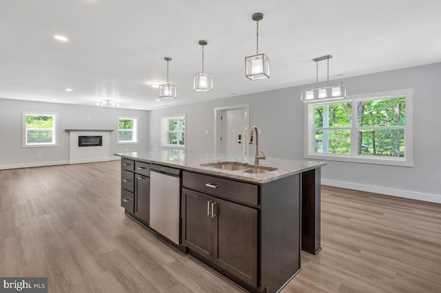 kitchen with light stone countertops, dishwasher, sink, hanging light fixtures, and dark brown cabinets