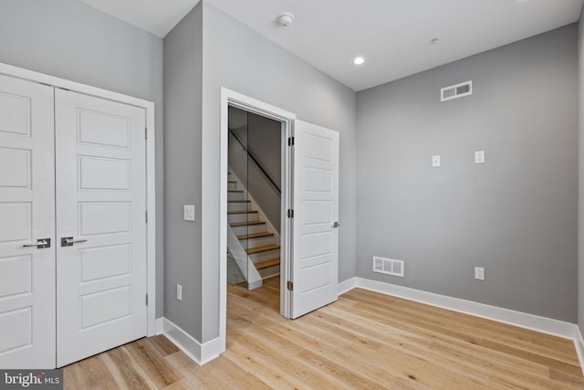 unfurnished bedroom with light wood finished floors, baseboards, visible vents, and a closet