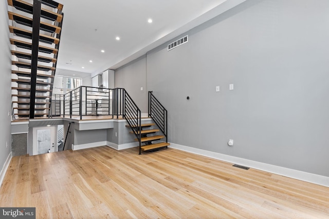 interior space with stairway, light wood-style flooring, visible vents, and baseboards