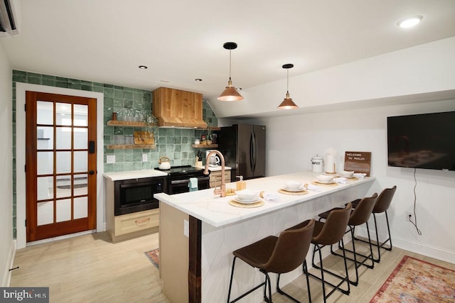 kitchen with kitchen peninsula, a kitchen breakfast bar, backsplash, custom range hood, and black appliances