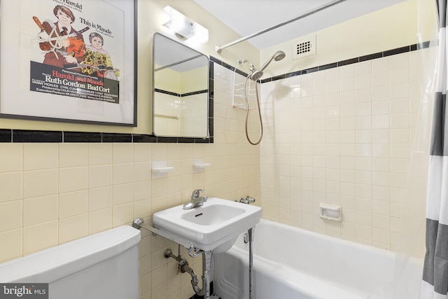 bathroom with tiled shower / bath combo, tile walls, and toilet