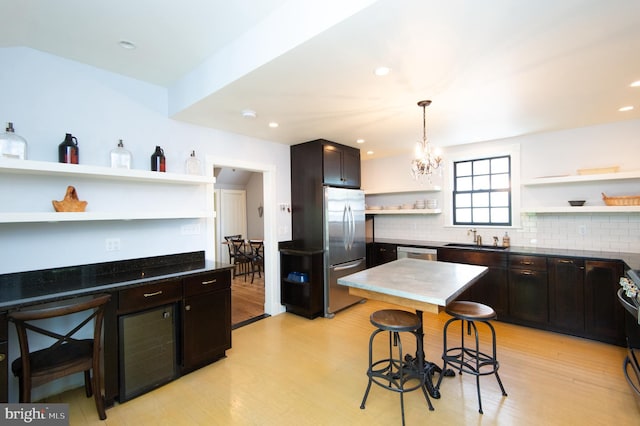 kitchen featuring light wood-type flooring, stainless steel appliances, sink, a chandelier, and hanging light fixtures