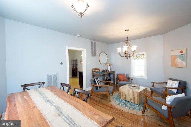 dining space with wood-type flooring and an inviting chandelier