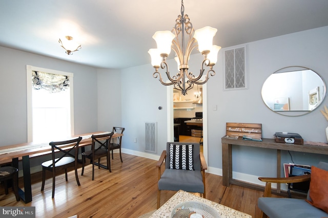 dining area with wood-type flooring and an inviting chandelier