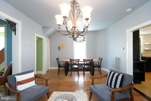 dining space featuring hardwood / wood-style flooring and an inviting chandelier