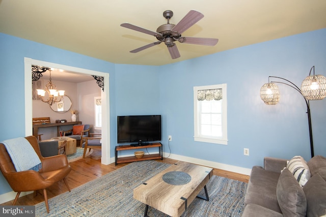 living room with ceiling fan with notable chandelier and wood-type flooring