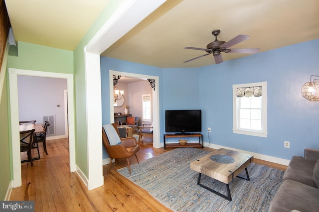 living room featuring light hardwood / wood-style flooring and ceiling fan with notable chandelier