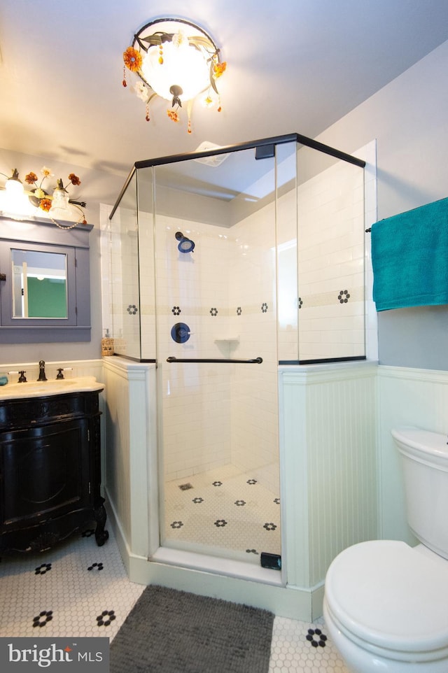 bathroom with tile patterned flooring, vanity, toilet, and walk in shower