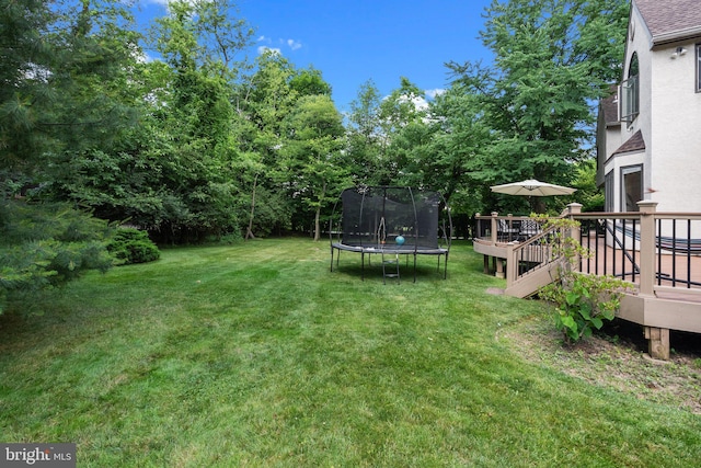 view of yard featuring a trampoline and a deck