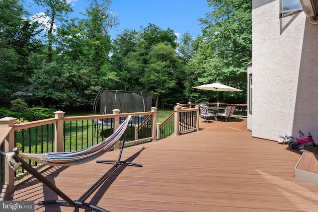 wooden deck with a trampoline and a lawn