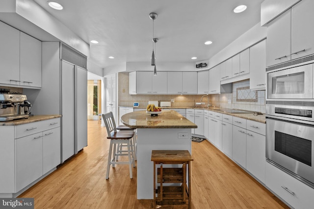 kitchen with pendant lighting, a center island, white cabinets, and light hardwood / wood-style floors