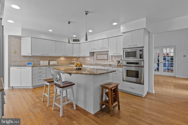 kitchen featuring a center island, light hardwood / wood-style flooring, white cabinets, and stainless steel appliances