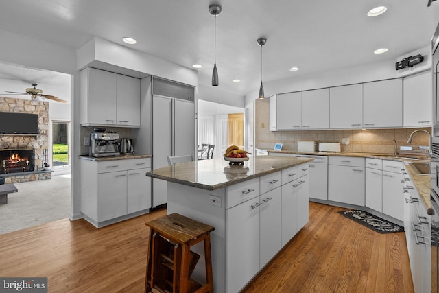 kitchen with a fireplace, a center island, white dishwasher, and white cabinetry