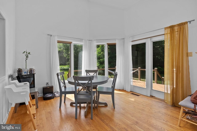 dining space featuring light hardwood / wood-style flooring and a towering ceiling