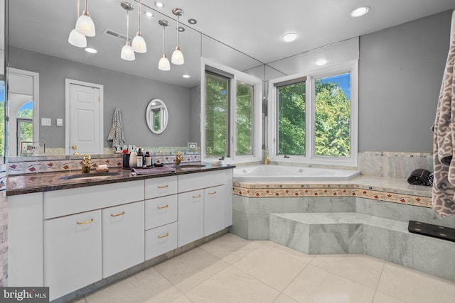 bathroom with vanity, tiled bath, tile patterned floors, and a healthy amount of sunlight