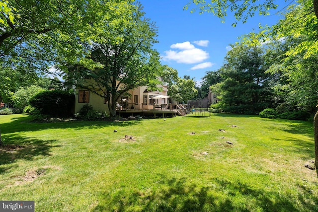 view of yard with a deck and a trampoline