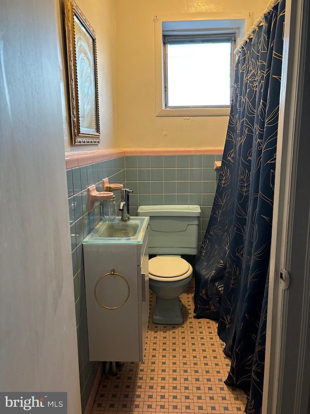 bathroom with tile patterned floors, vanity, toilet, and tile walls