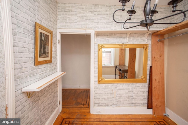 corridor with hardwood / wood-style floors and brick wall