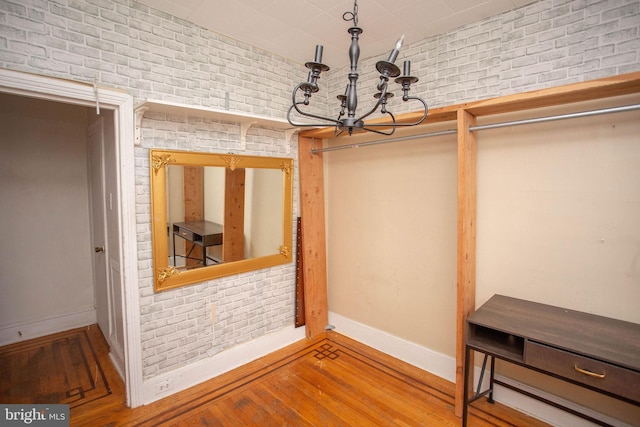 spacious closet featuring hardwood / wood-style flooring and an inviting chandelier