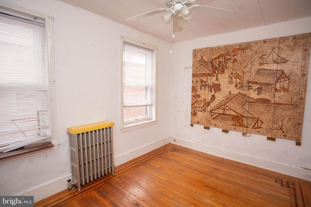 spare room featuring radiator, ceiling fan, and hardwood / wood-style flooring