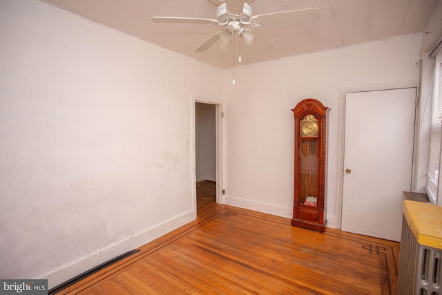 spare room with ceiling fan, wood-type flooring, and radiator