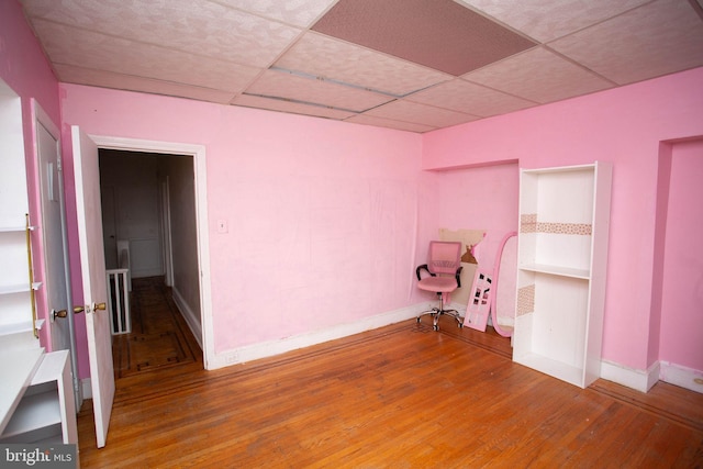 empty room featuring a paneled ceiling and hardwood / wood-style floors