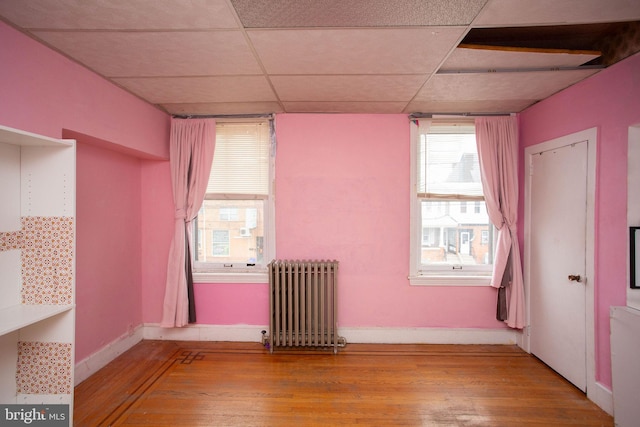 spare room featuring radiator, a paneled ceiling, and light hardwood / wood-style flooring