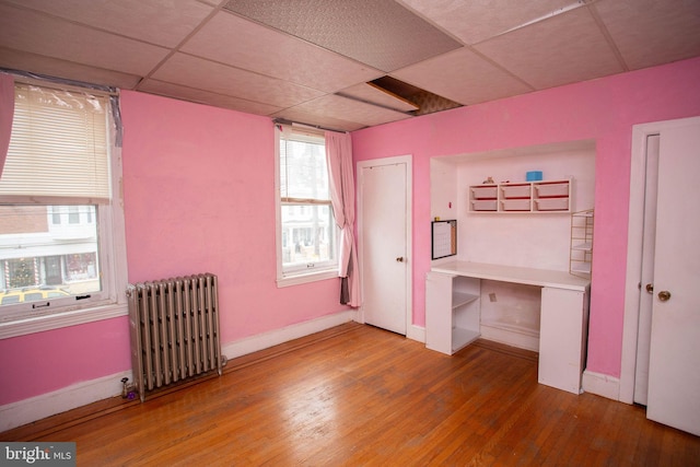 bedroom featuring radiator, a paneled ceiling, and wood-type flooring