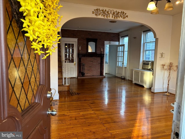 entrance foyer with a brick fireplace, dark hardwood / wood-style flooring, radiator heating unit, brick wall, and a chandelier