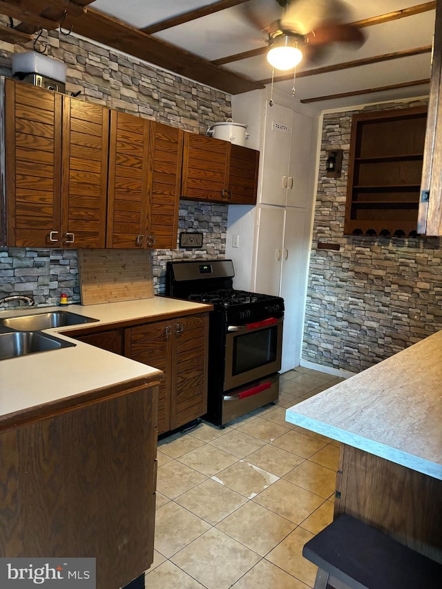 kitchen featuring light tile patterned floors, gas stove, ceiling fan, and backsplash