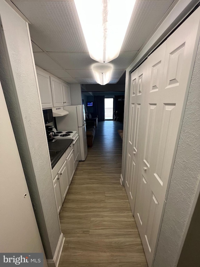 kitchen featuring dark hardwood / wood-style floors, white refrigerator, and white cabinetry