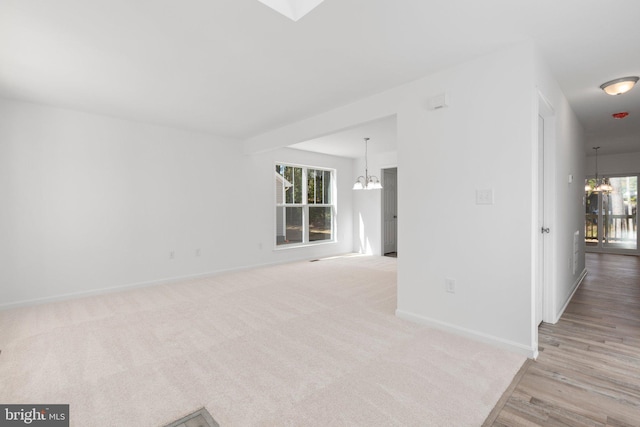 spare room featuring a notable chandelier and light wood-type flooring