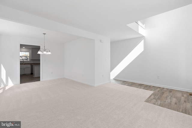 unfurnished living room with a chandelier and light hardwood / wood-style floors