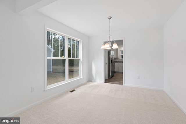 carpeted spare room with a chandelier