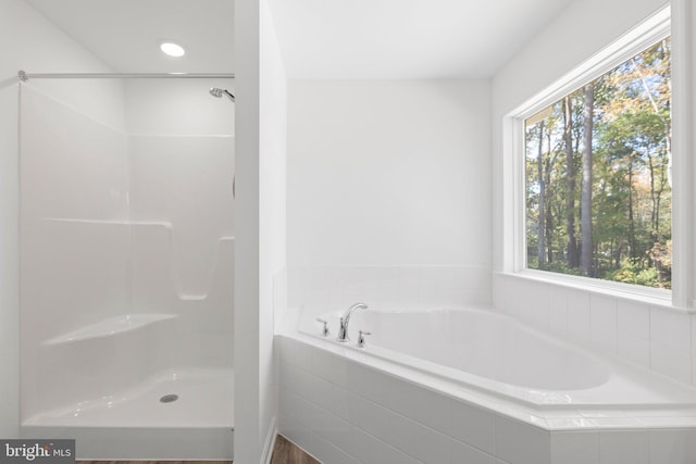 bathroom featuring a healthy amount of sunlight and tiled tub